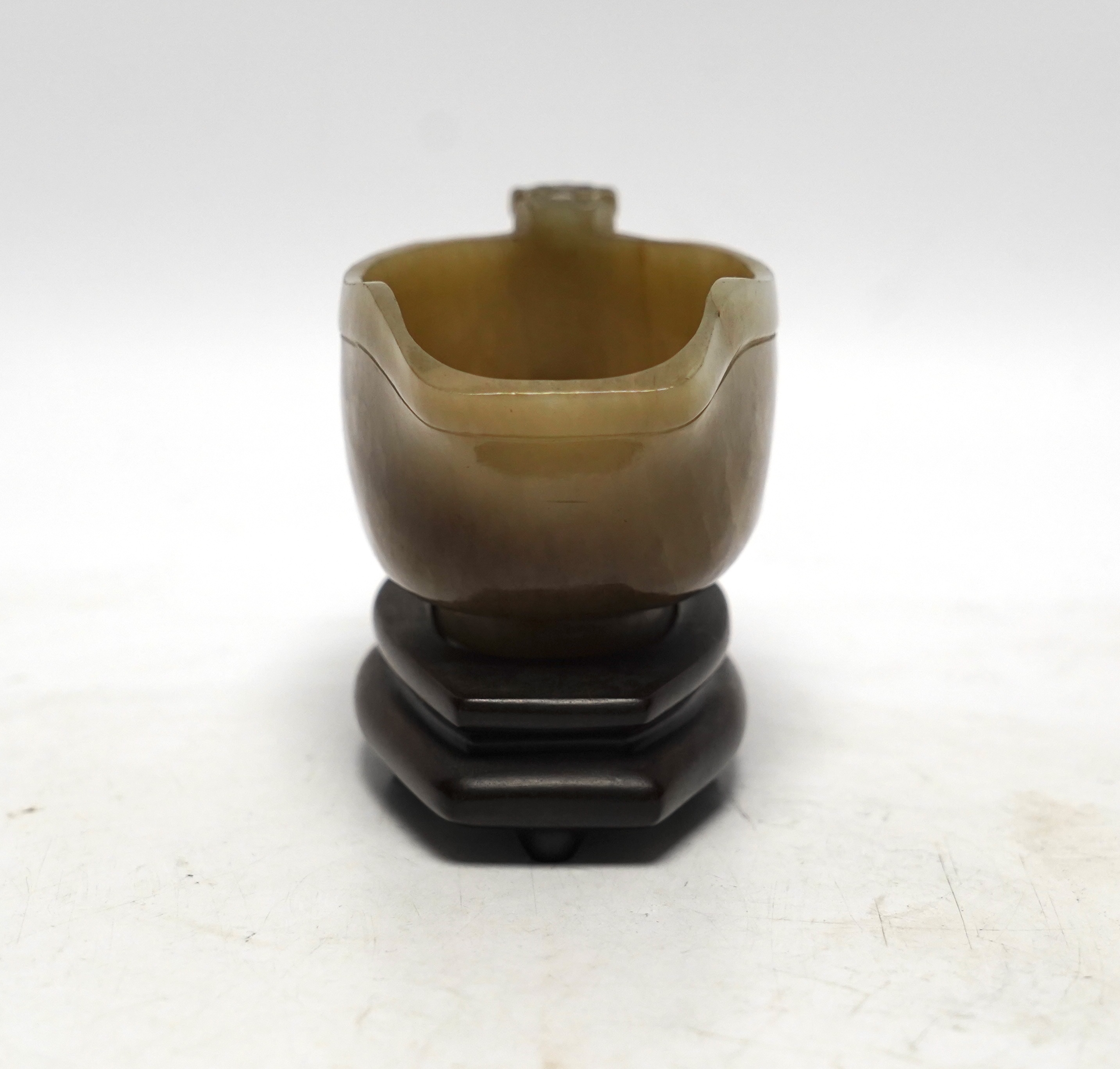 An 18th century Chinese archaistic jade pouring vessel, yi, with carved dragon handle, 6cm high, on a hardwood stand